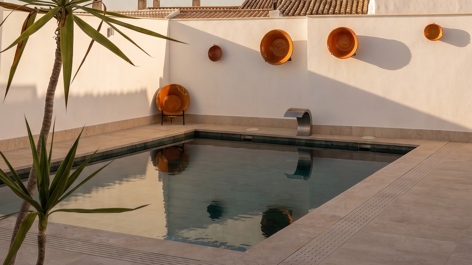La piscina del patio entre yucas, con los tejados de Zuheros al fondo