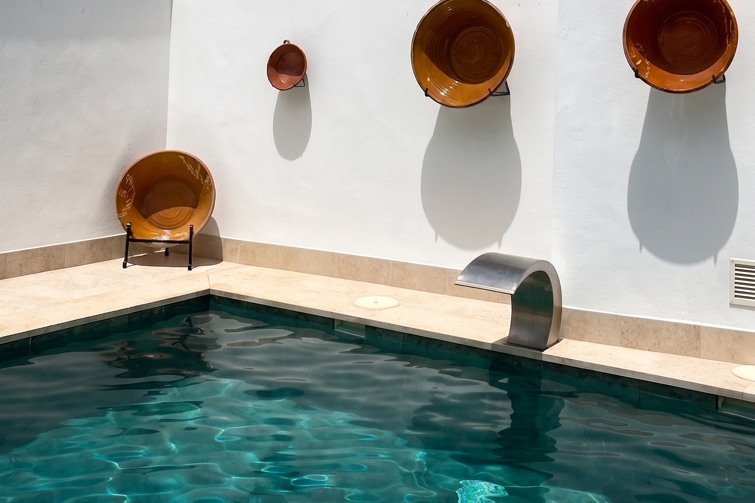 La piscina y el muro encalado con lebrillos de barro colgados